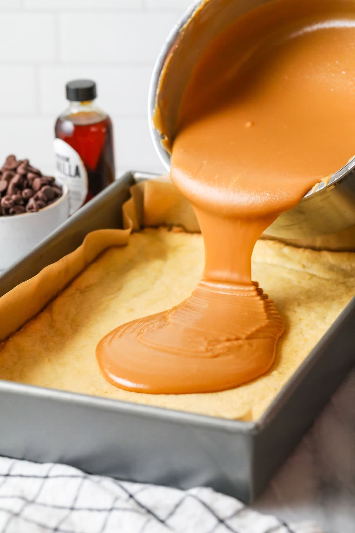 Pouring caramel over the shortbread crust for Millionaire's shortbread.