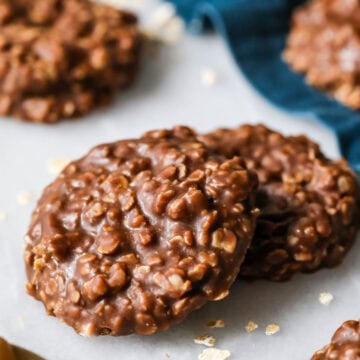 Two no bake cookies on marble with blue cloth in background.
