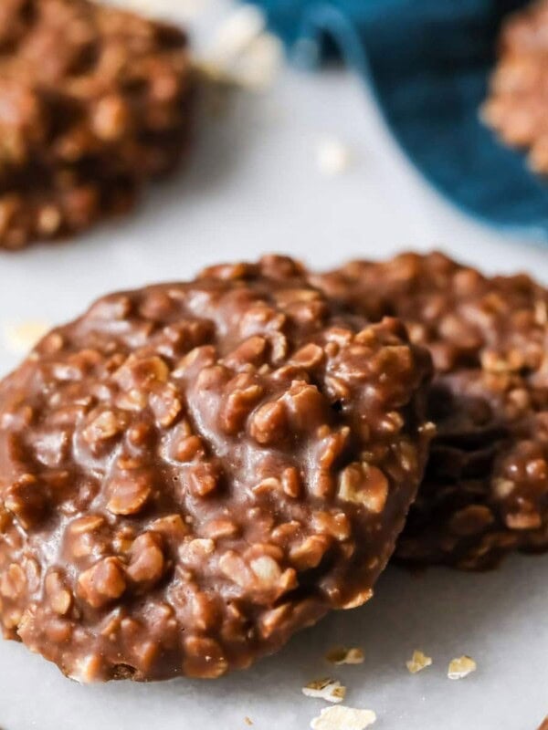 Two no bake cookies on marble with blue cloth in background.