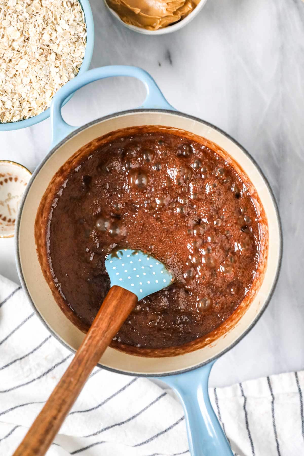Chocolate mixture boiling in blue saucepan.