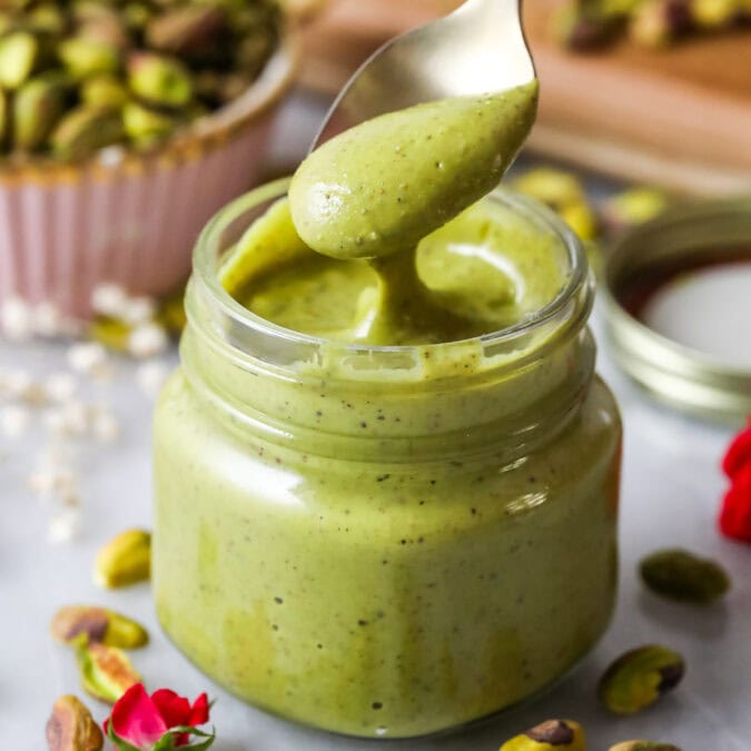 Spoon dipping into a small jar of homemade pistachio cream.