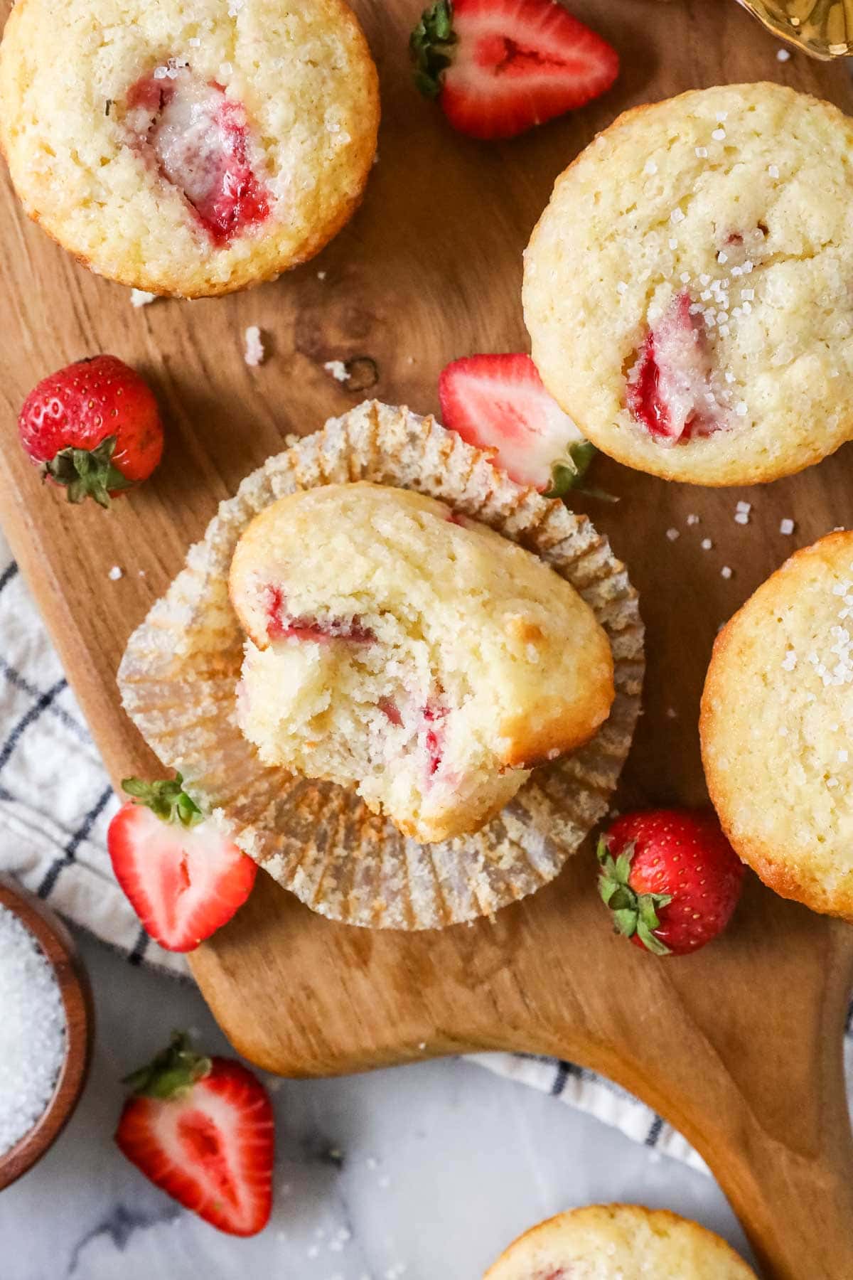 Overhead view of strawberry muffins with the center muffin missing a bite.