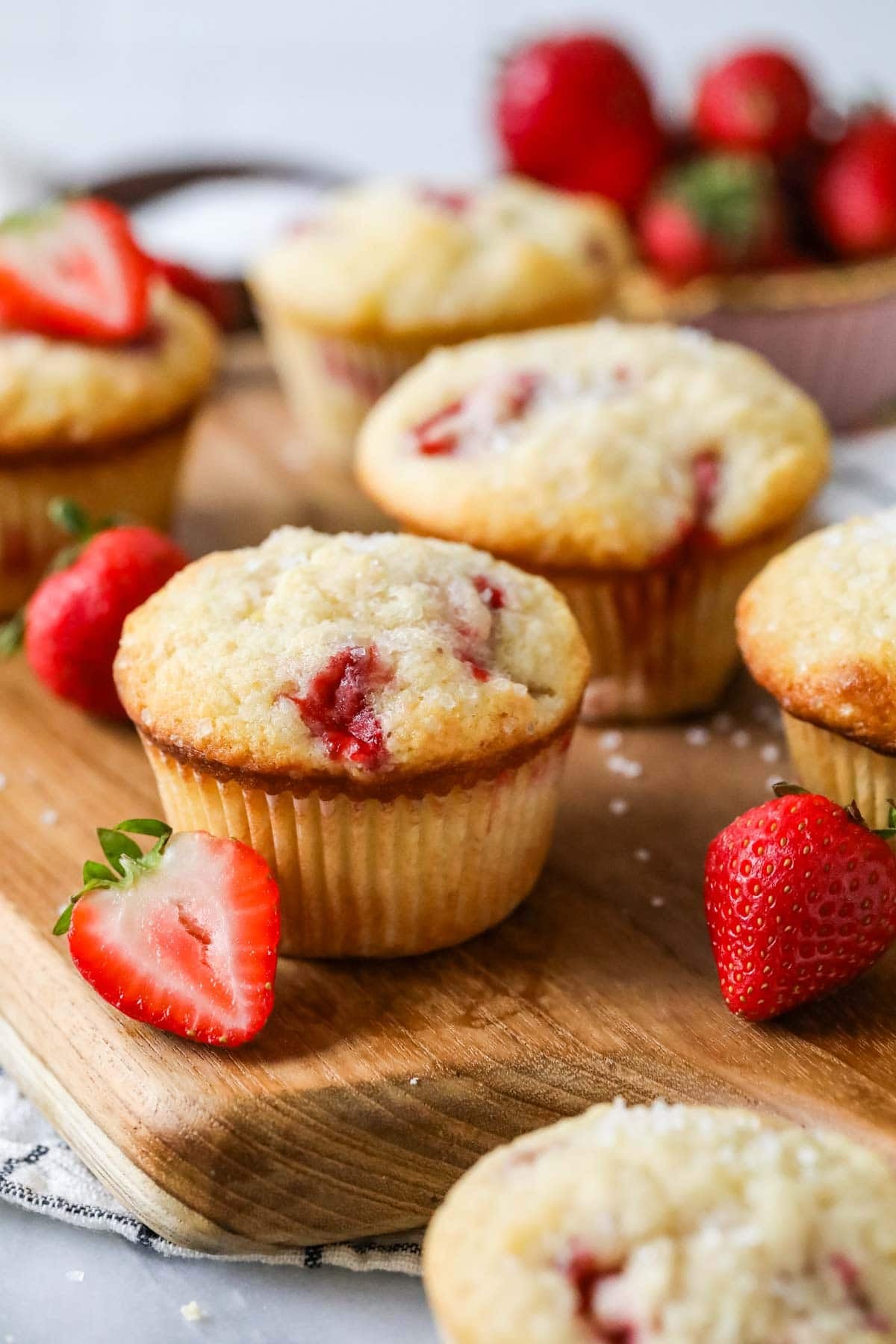 Muffins made with fresh strawberries on a wood serving platter.