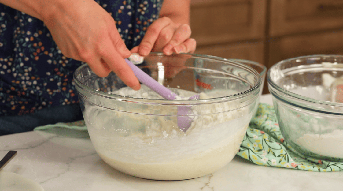 Flour mixture being folded into creamed butter, sugar, and oil.
