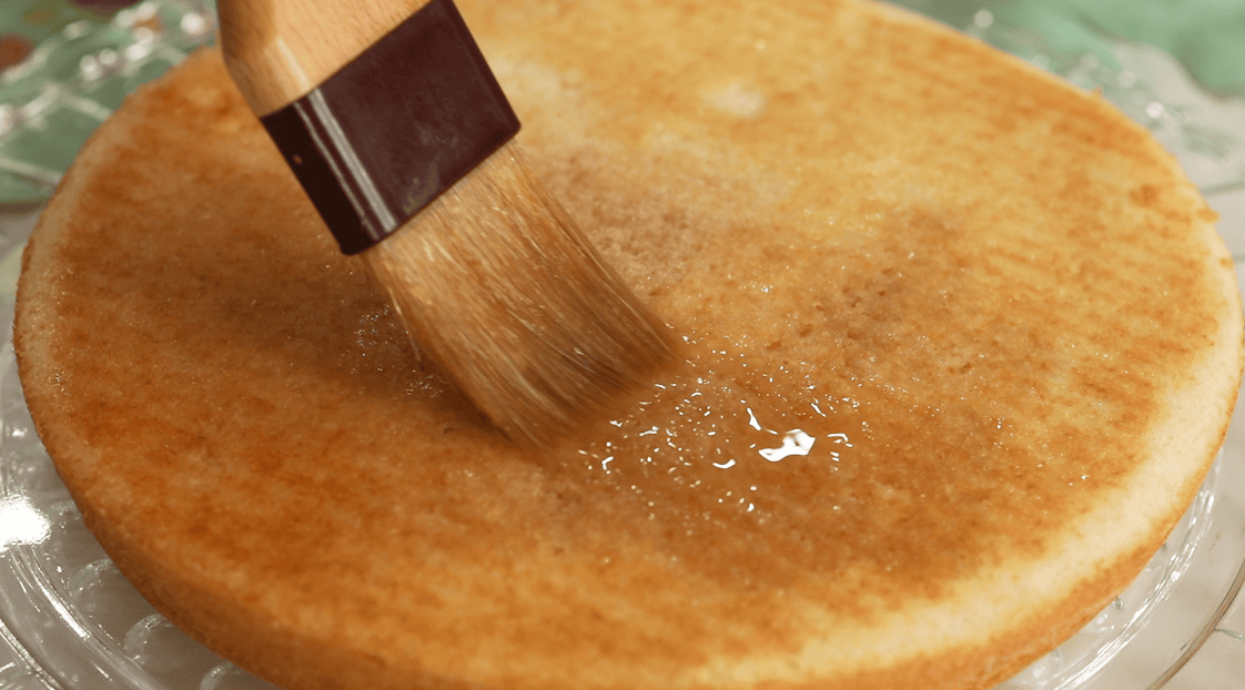 Brushing a rum and coffee simple syrup over vanilla cake layers for a tiramisu layer cake.