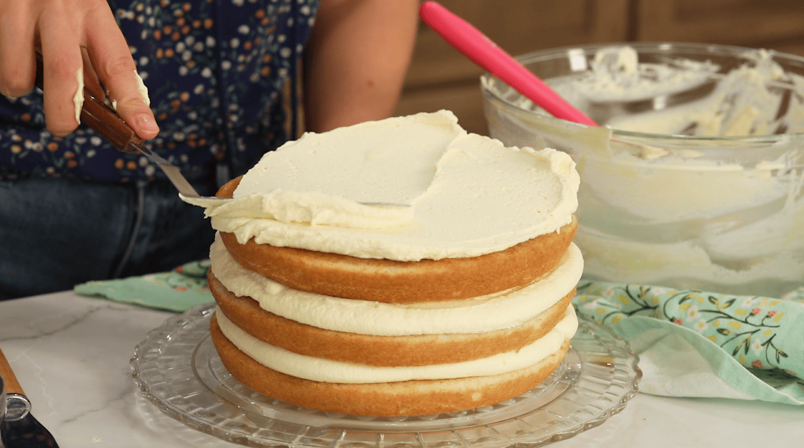 Spreading thick layers of frosting between rum and coffee soaked cake layers.