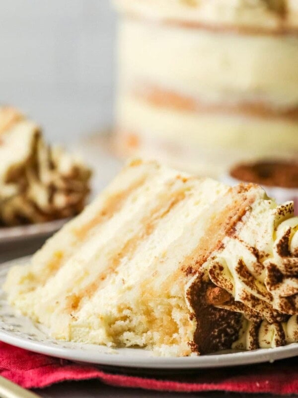 Slice of tiramisu layer cake with one bite missing on a plate.