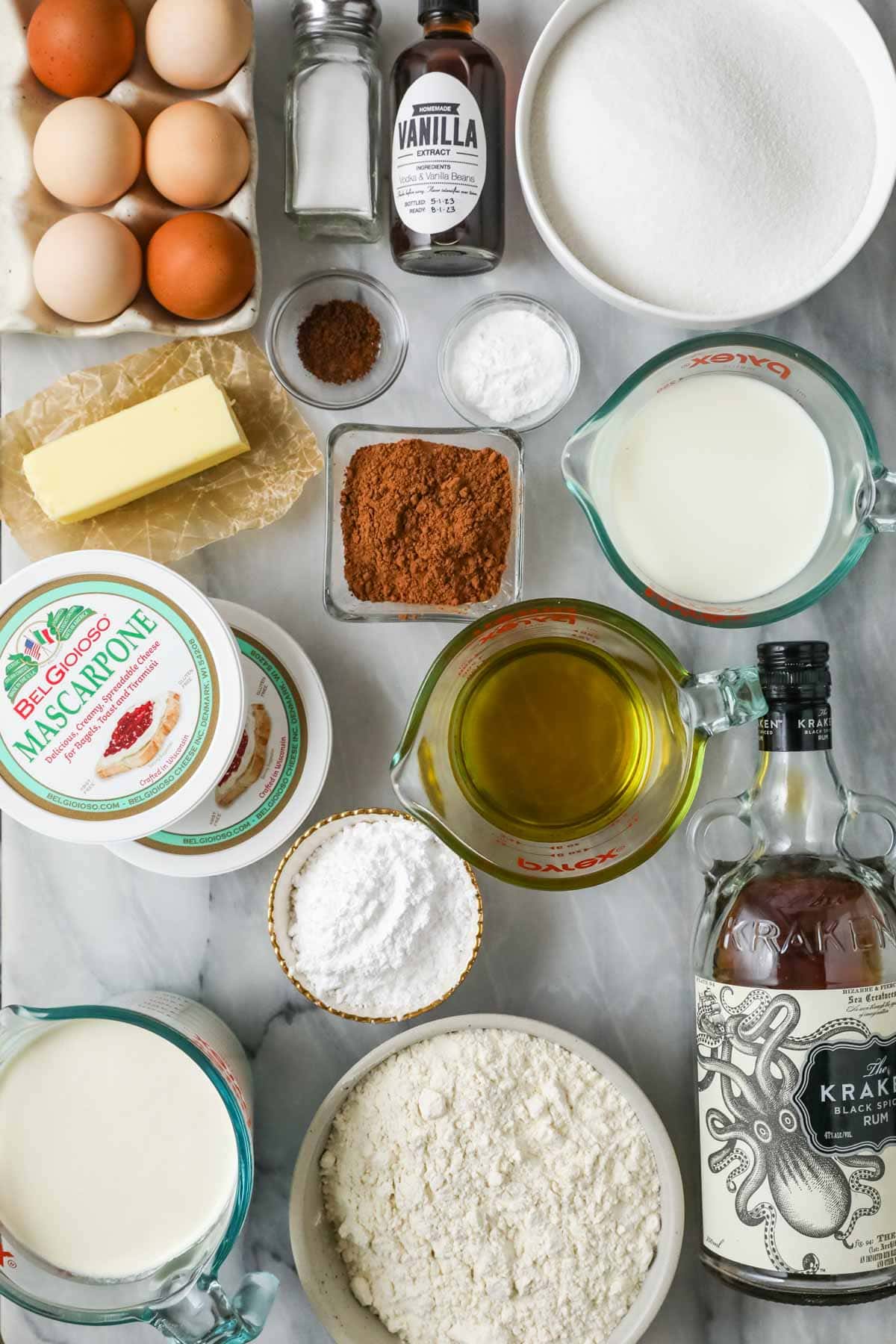 Overhead view of ingredients including rum, mascarpone, eggs, cocoa powder, and more.