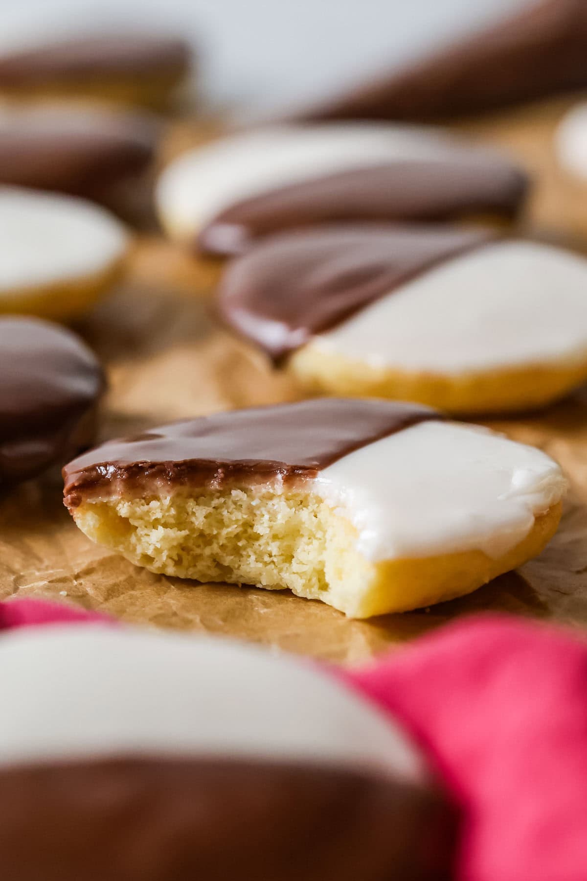 Bite missing from a cookie that's been half dipped in white frosting and half dipped in chocolate frosting.