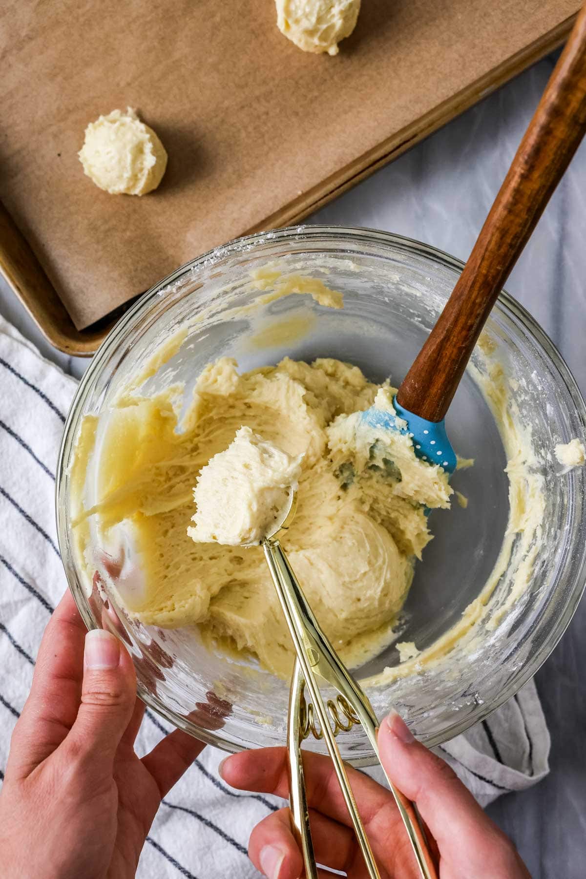 Overhead view of a pale cookie dough being scooped from a bowl.
