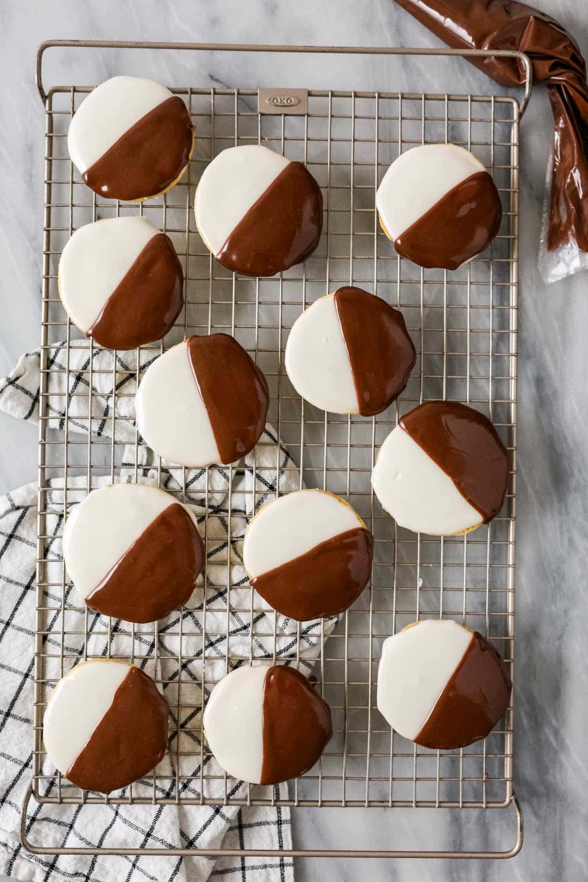 Overhead view of black and white cookies on a wire cooling rack.