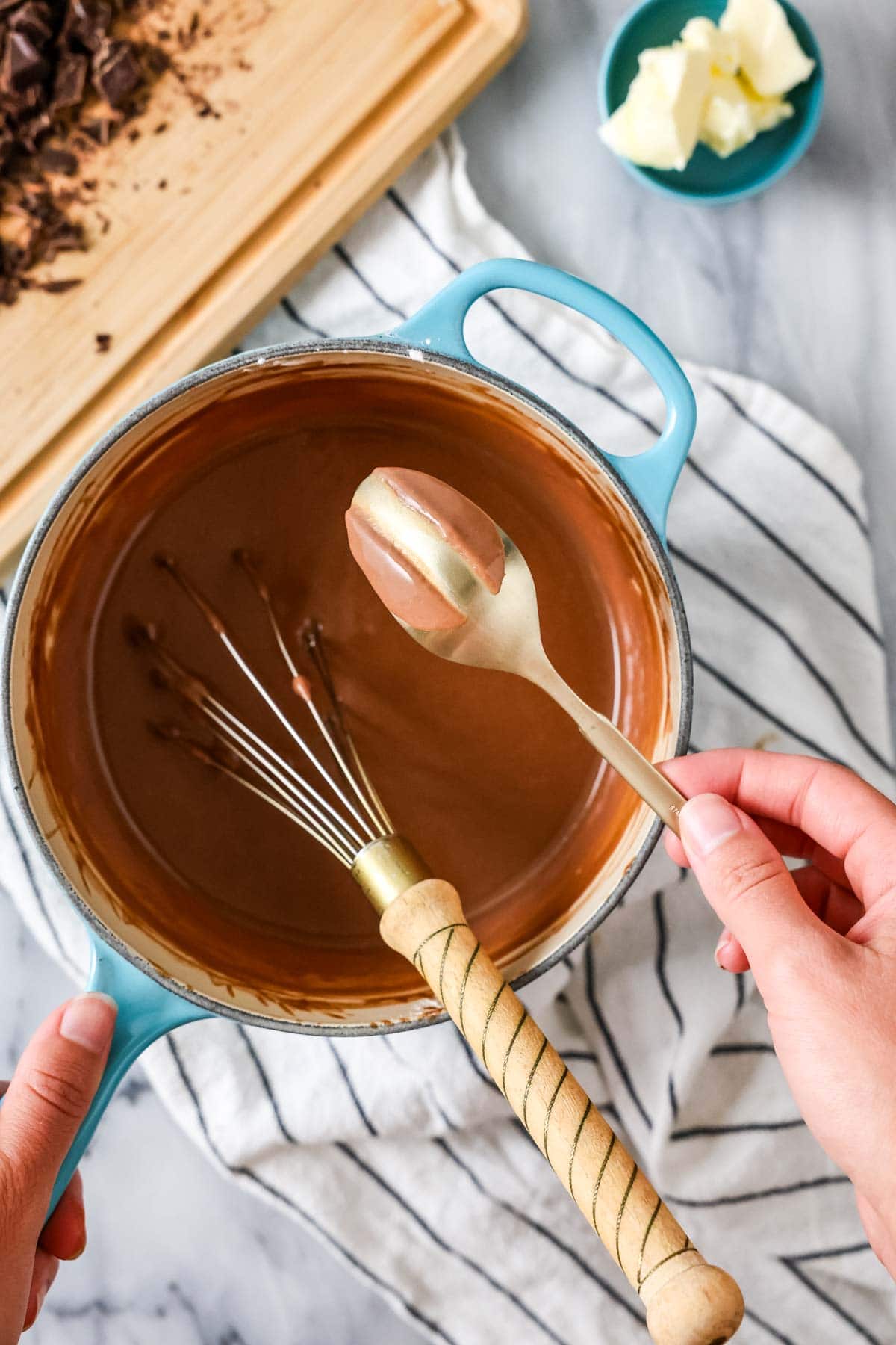 Overhead view of a spoon being lifted out of a pudding mixture to show it has thickened properly. 