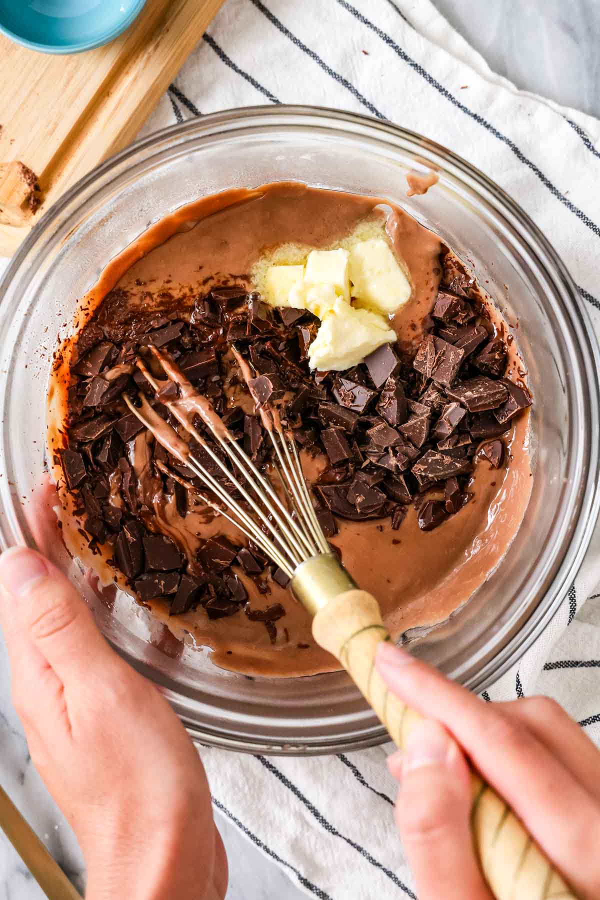 Overhead view of butter and chocolate being whisked into a pudding mixture.