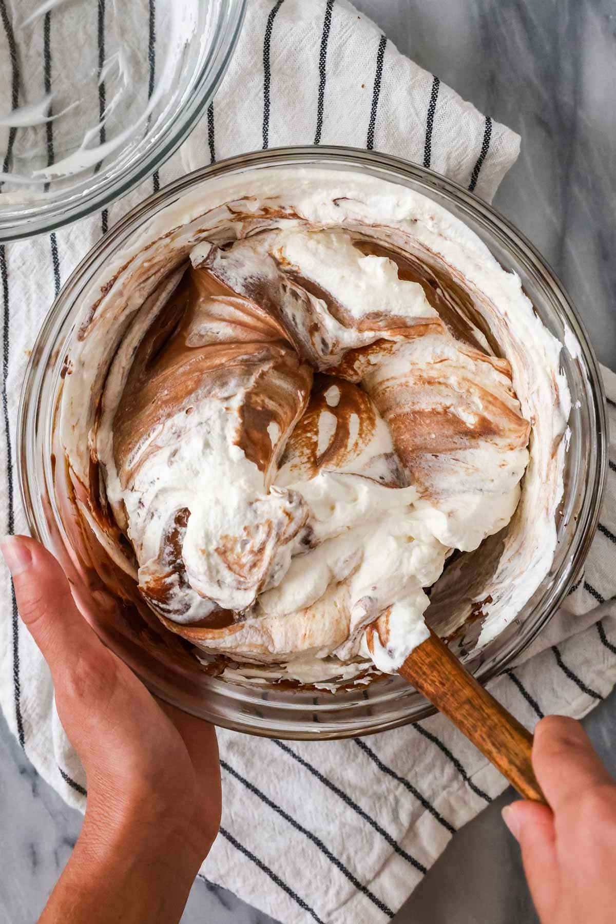 Overhead view of pudding and whipped cream being folded together.