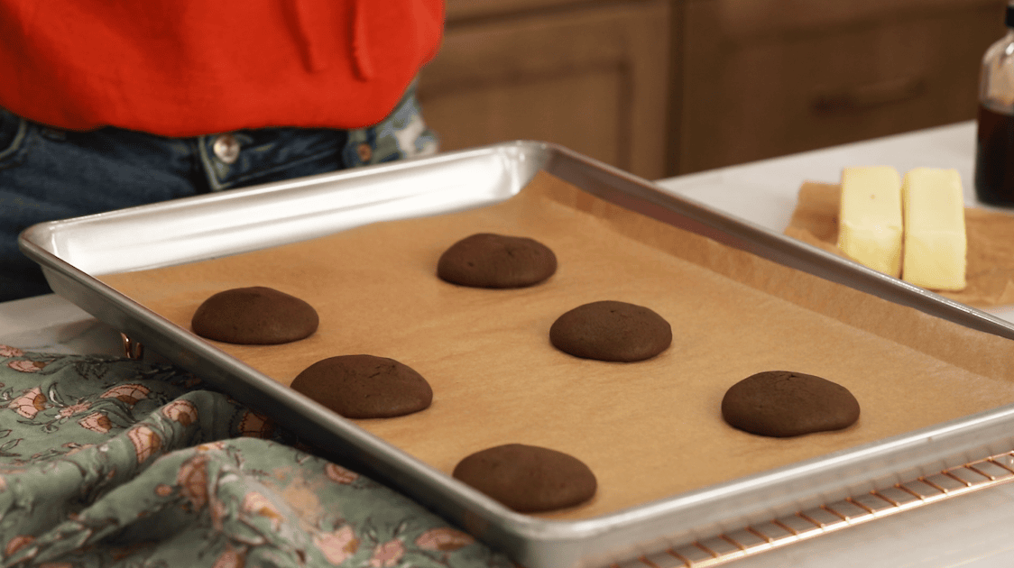 Chocolate cookie shells on a baking sheet after baking.