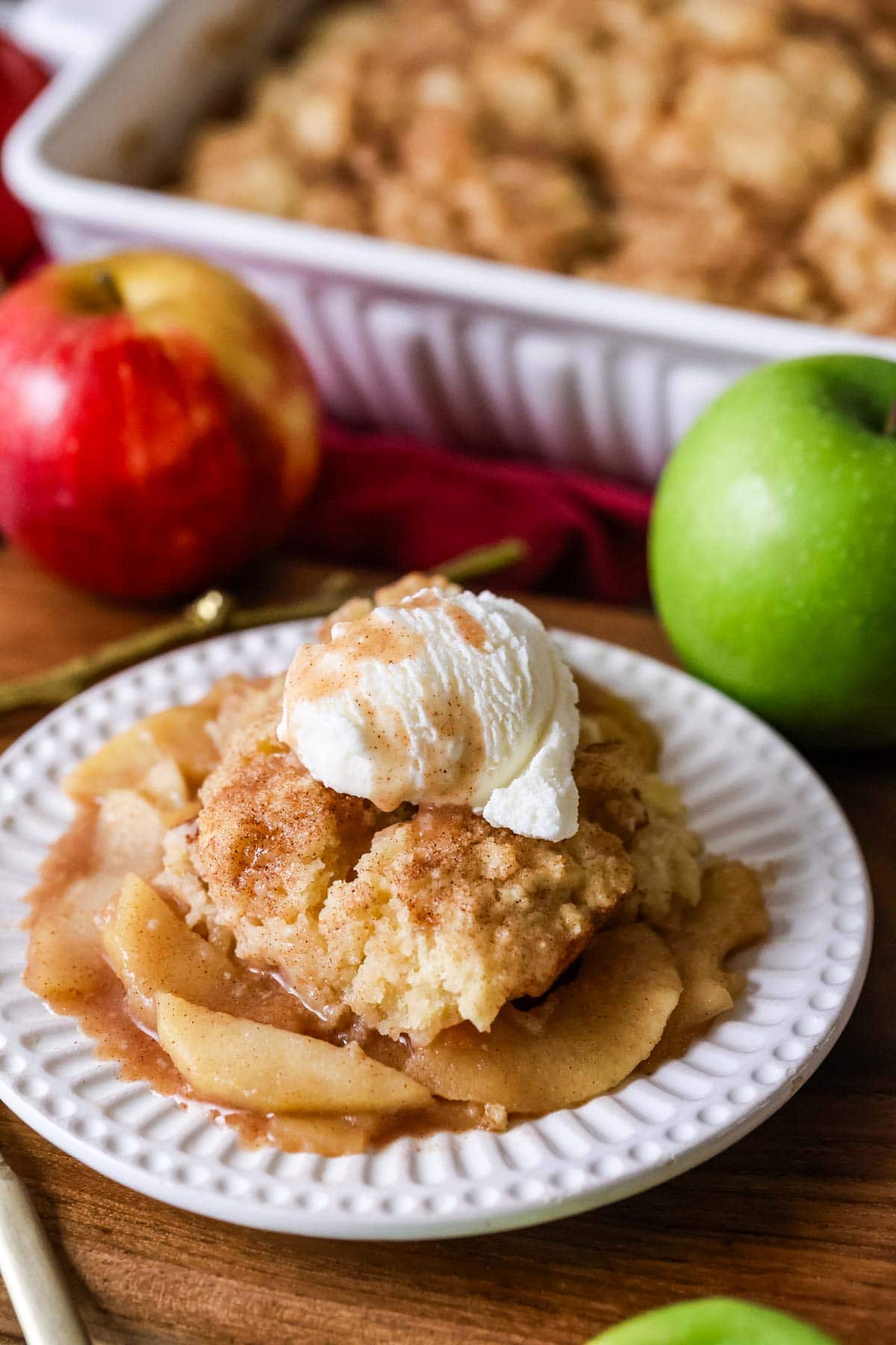 Portion of cobbler made with apples topped with vanilla ice cream and cinnamon sugar.
