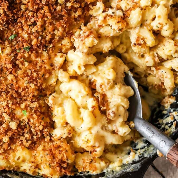 Close-up of creamy, cheesy baked mac and cheese in dish with serving spoon and crispy panko.