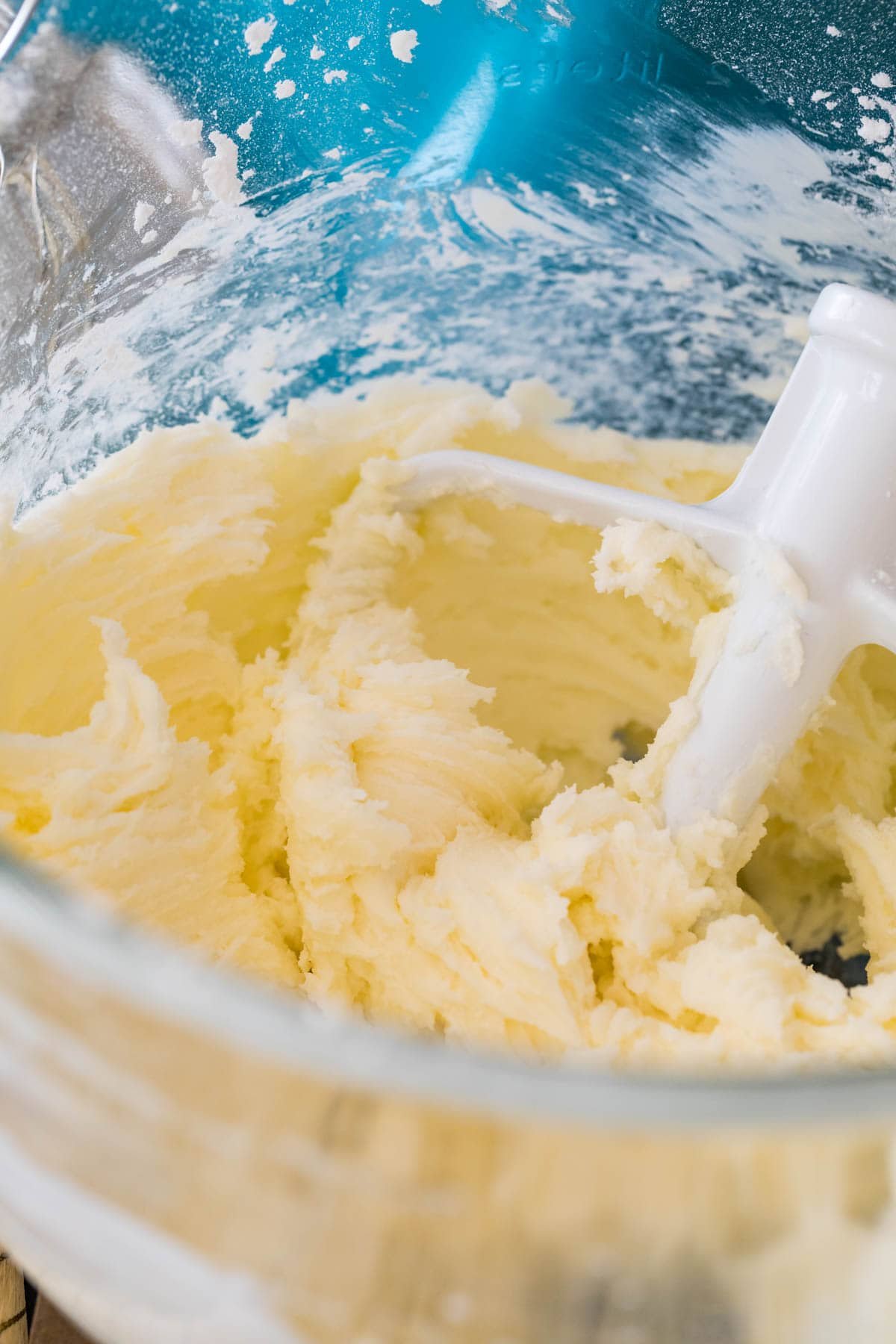 Close-up view of a bowl of frosting after being stirred with a paddle attachment.