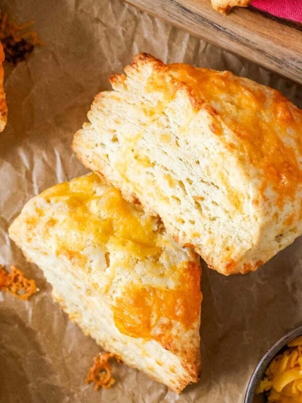 Overhead view of wedge shaped cheese scones with the top scone on its side to show flaky layers.