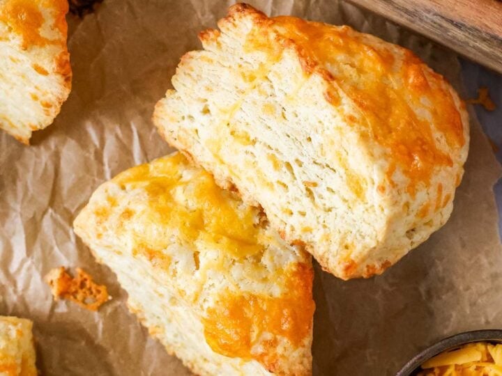 Overhead view of wedge shaped cheese scones with the top scone on its side to show flaky layers.