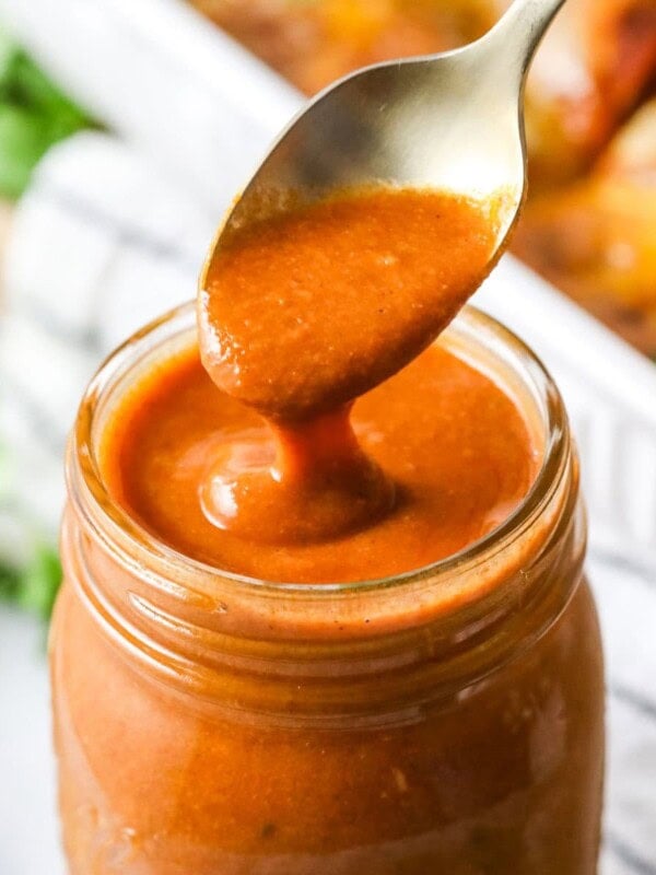 Homemade enchilada sauce being spooned from a jar.