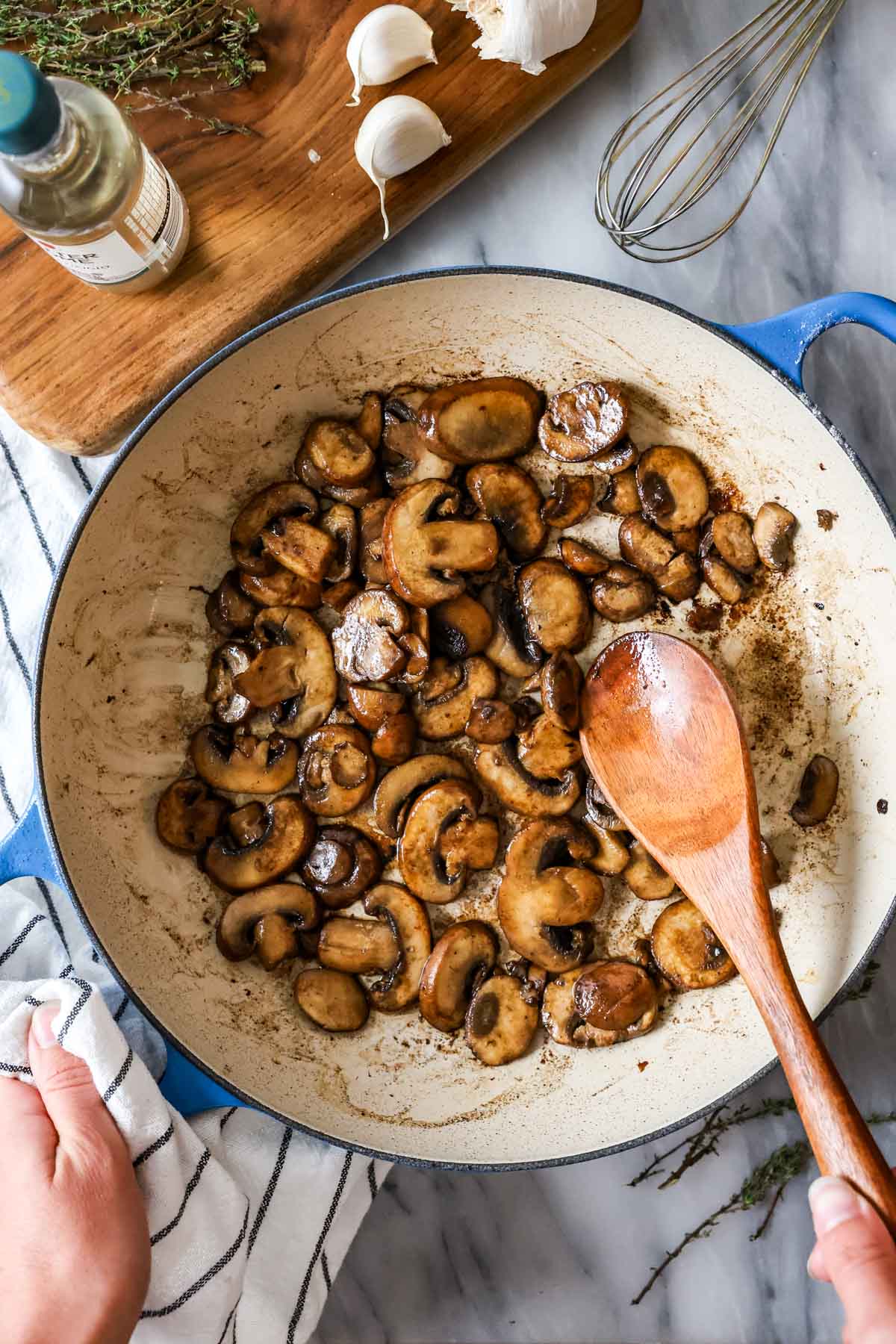 Overhead view of mushrooms sautéing in a skillet.