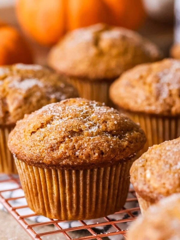 Sourdough pumpkin muffins topped with coarse sugar on a cooling rack.