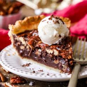 Slice of chocolate pecan pie topped with a scoop of ice cream.