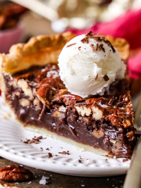 Slice of chocolate pecan pie topped with a scoop of ice cream.