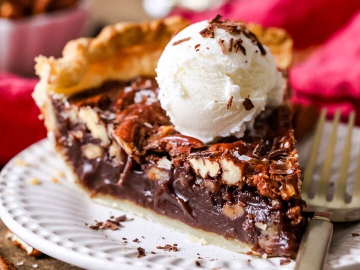 Slice of chocolate pecan pie topped with a scoop of ice cream.