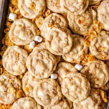 Overhead view of cornflake cookies surrounded by cornflakes and mini marshmallows.