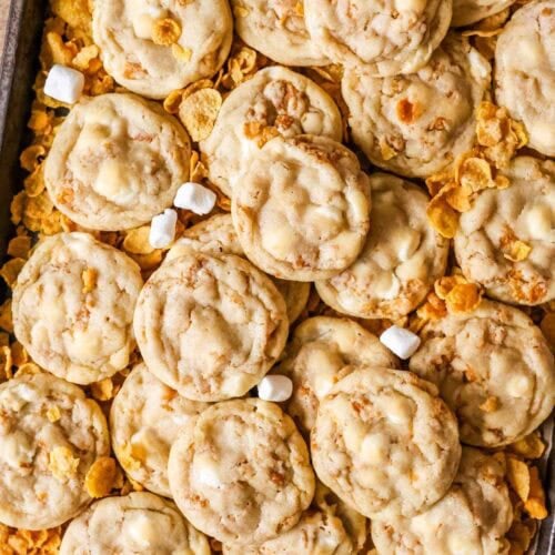 Overhead view of cornflake cookies surrounded by cornflakes and mini marshmallows.