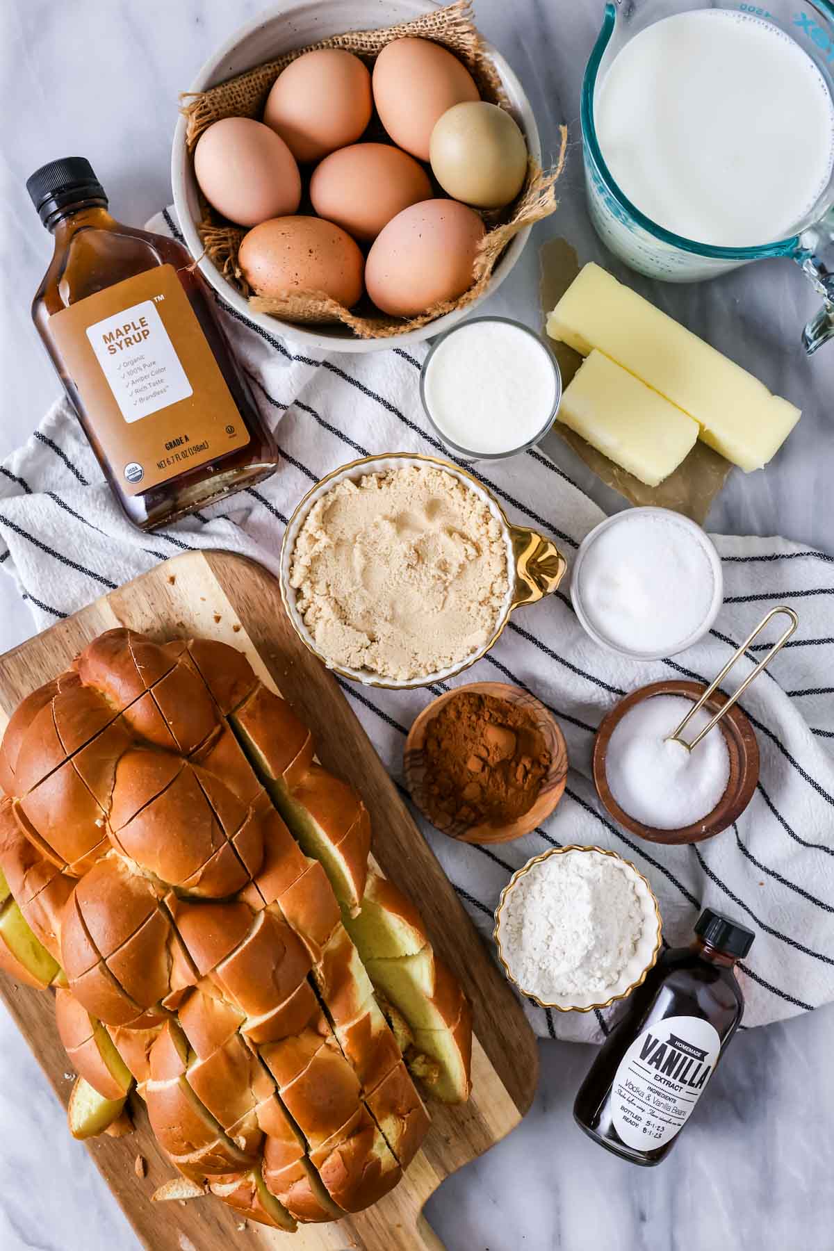 Overhead view of ingredients including challah bread, eggs, maple syrup, and more.