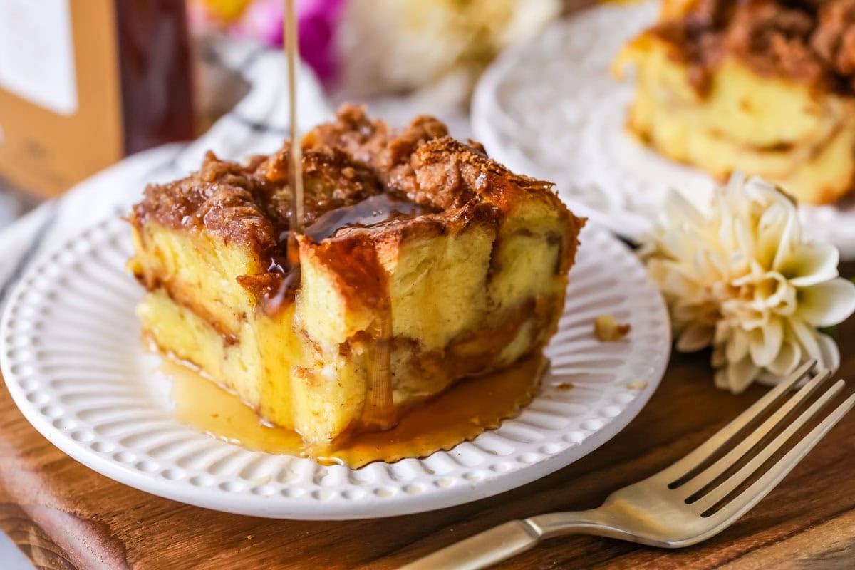 Maple syrup being drizzled over a square slice of French toast casserole.
