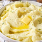 Bowl of mashed potatoes topped with a melting pat of butter.