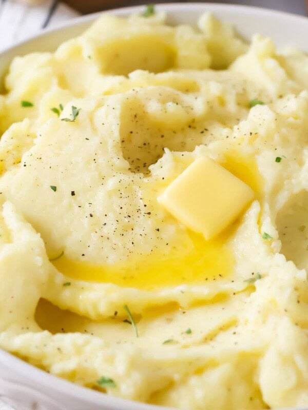 Bowl of mashed potatoes topped with a melting pat of butter.