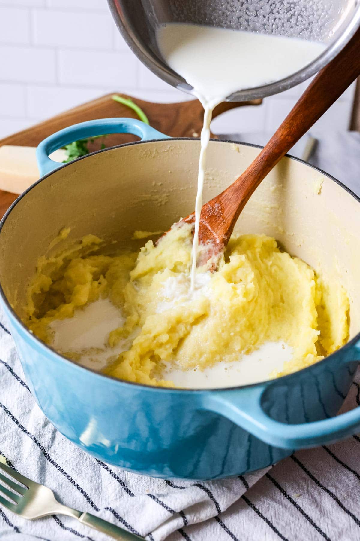 Milk being stirred into potatoes after mashing.