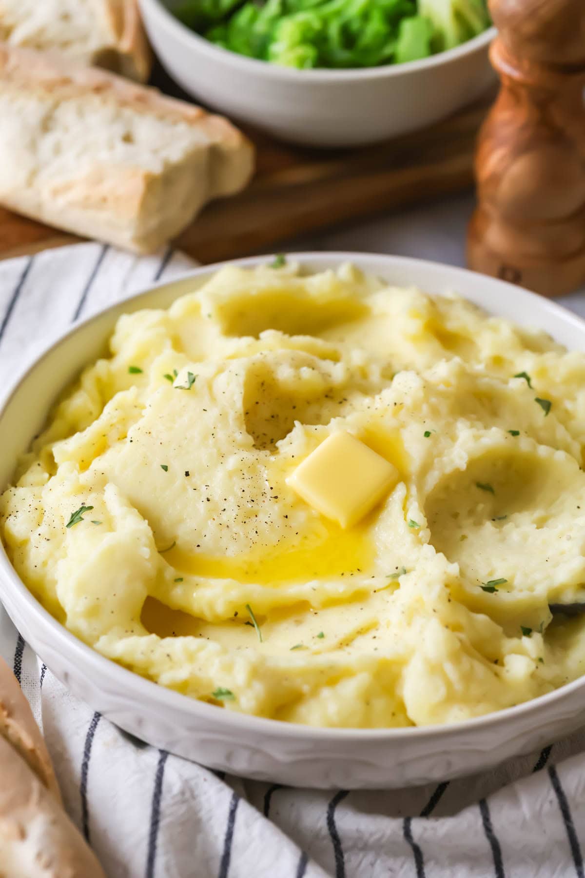 Bowl of mashed potatoes topped with a melting pat of butter.