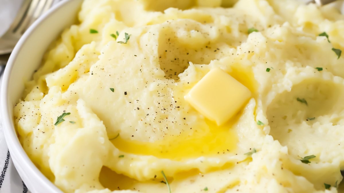 Bowl of mashed potatoes topped with a melting pat of butter.