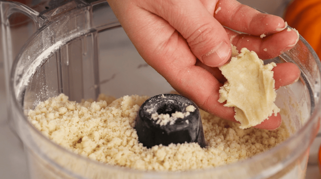 Hands showing a crumbly dough that's staying together after being pinched.