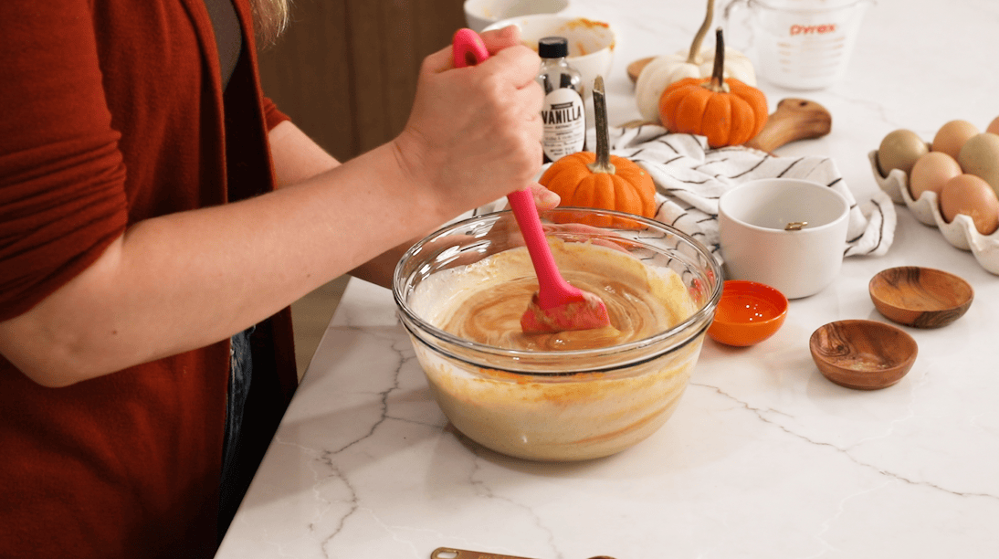 Spatula stirring a pumpkin pie filling together.