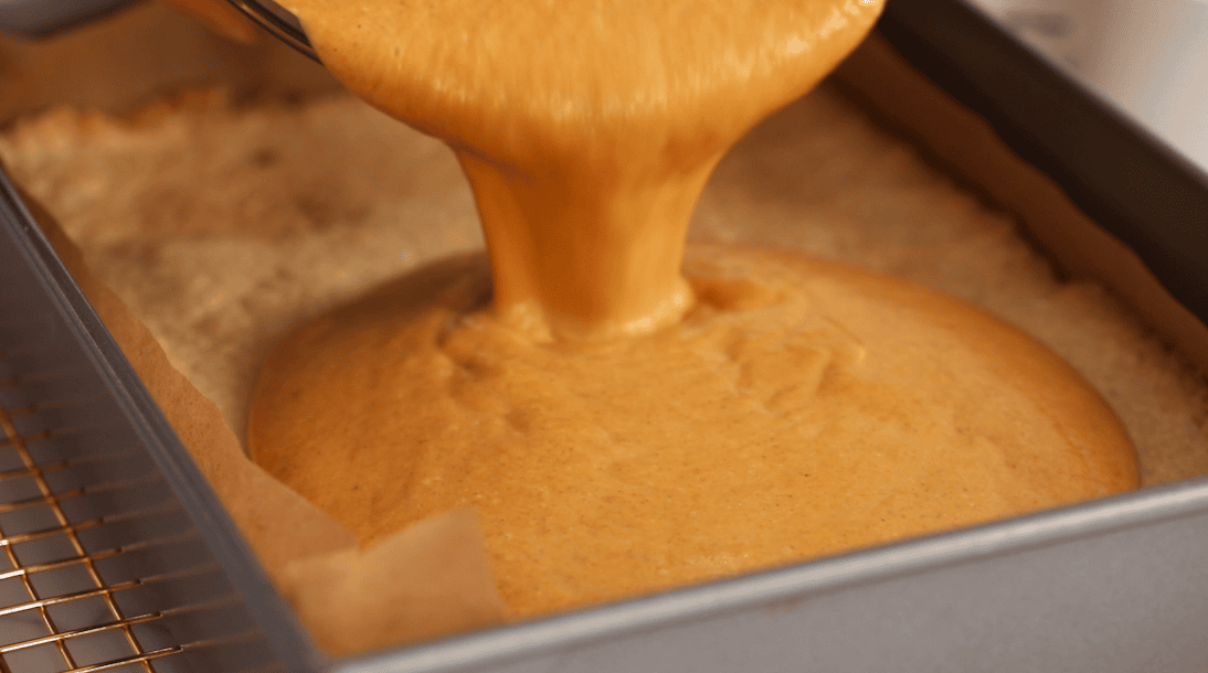 Pumpkin pie filling being poured over a shortbread crust.