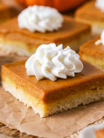 Individual pumpkin pie bars topped with whipped cream.