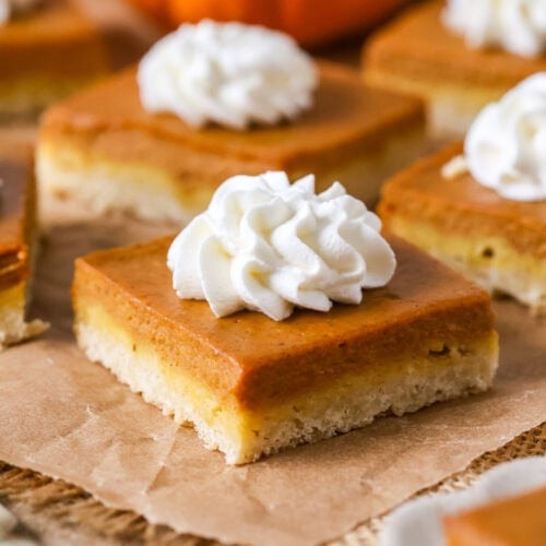 Individual pumpkin pie bars topped with whipped cream.
