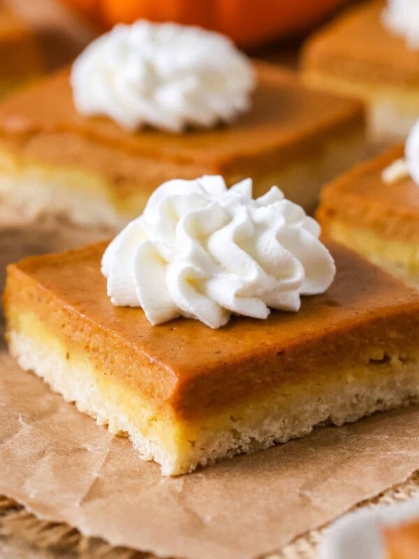 Individual pumpkin pie bars topped with whipped cream.