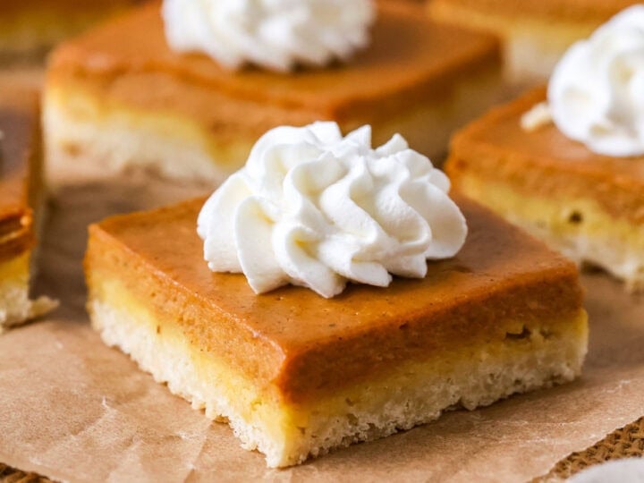 Individual pumpkin pie bars topped with whipped cream.