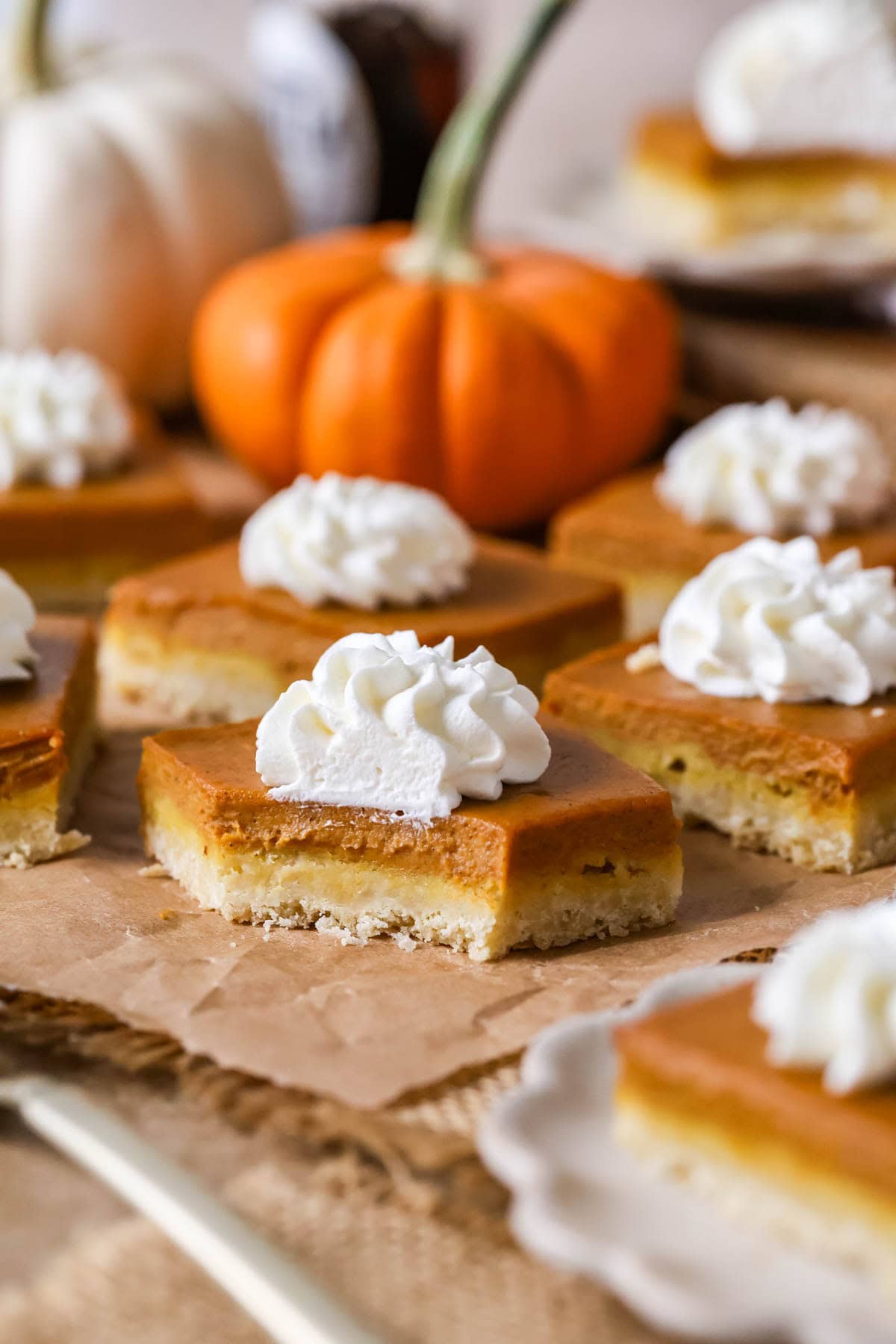 Bite missing from a bar made with a shortbread crust, pumpkin filling, and whipped cream topping.
