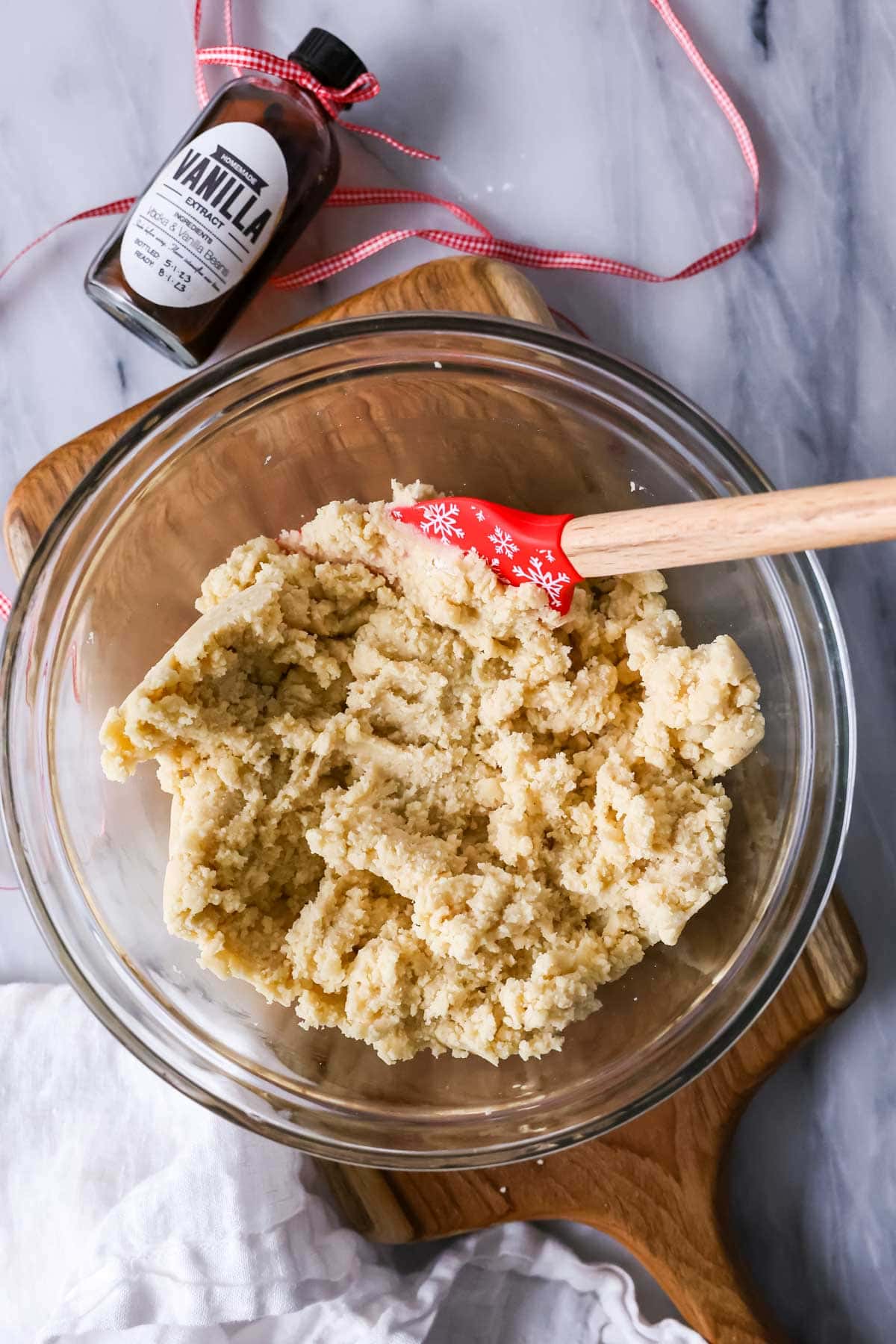 Overhead view of a bowl of cookie dough with a red spatula in it.
