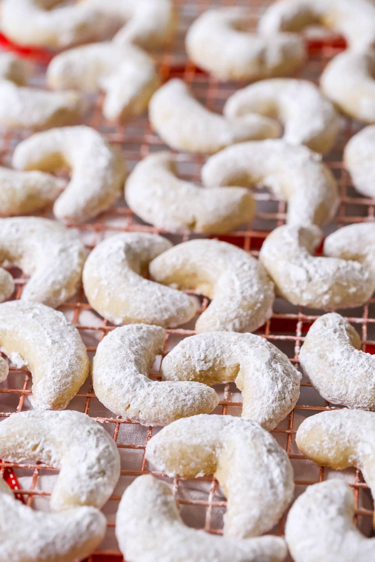 Close-up view of almond crescent cookies on a cooling rack.