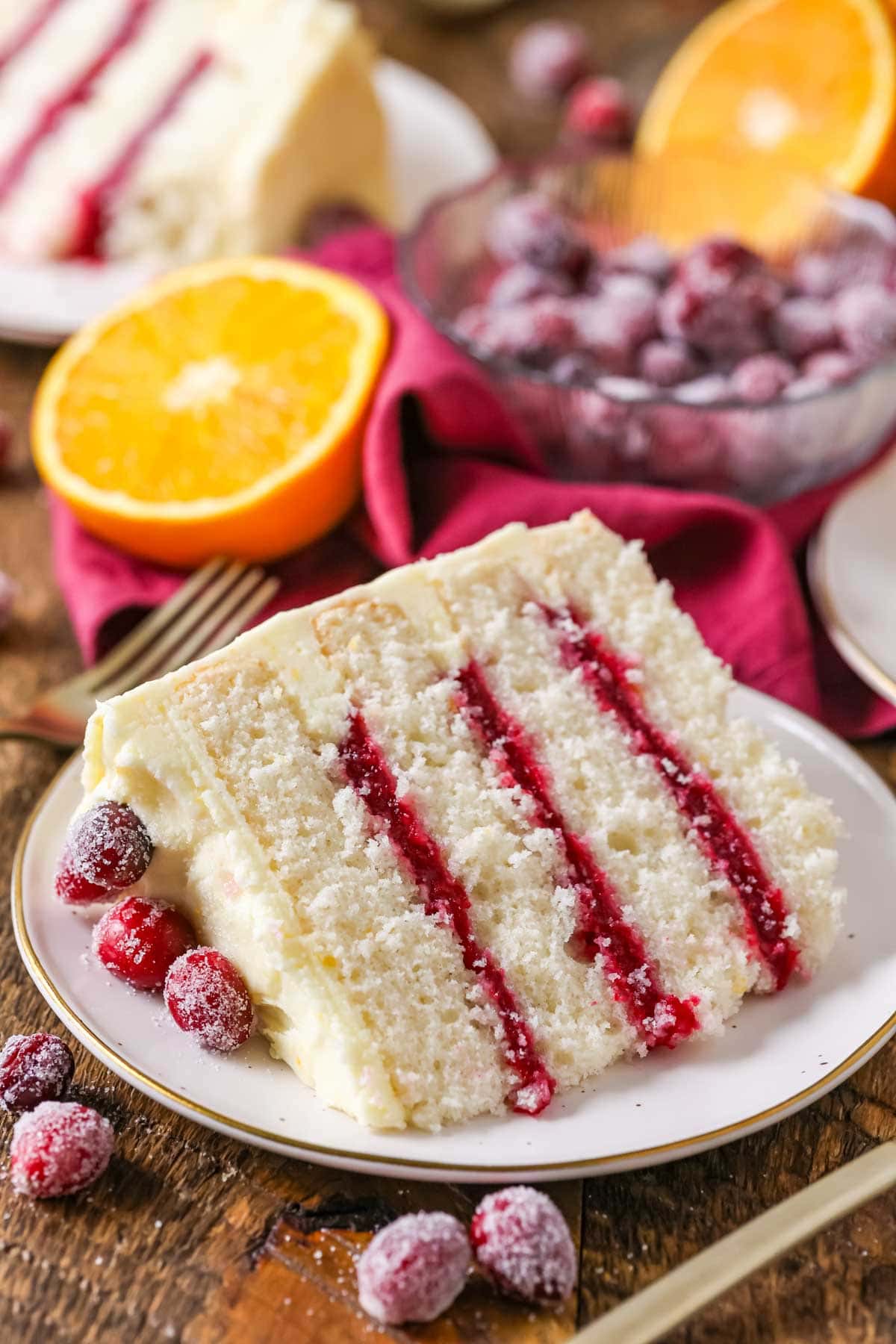 Slice of cake with four layers of white cake, three layers of cranberry filling, and a coating of orange cream cheese frosting.